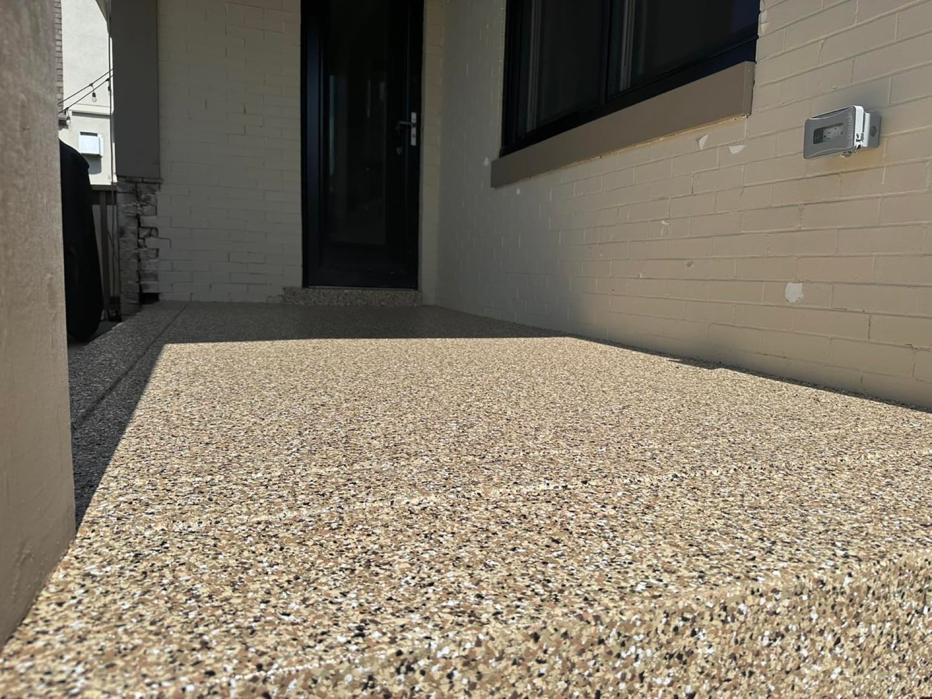 Gray flake patio coating against white brick — Westlake, OH